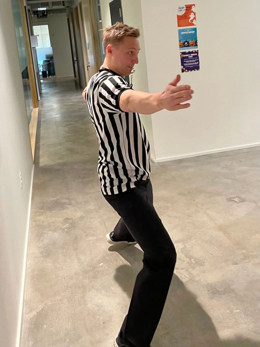 Sproutbox teammate in a referee costume making a call in the office hallway
