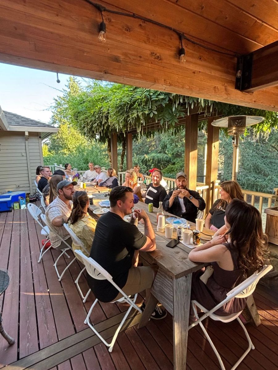 Sproutbox teammates chatting around a long table on a wooden deck at sunset