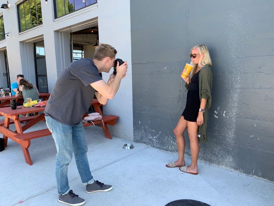 Sproutbox photographer shooting a model against a gray wall outside during a photo shoot