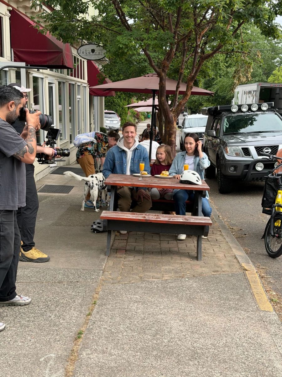Sproutbox crew filming people at a sidewalk picnic table outside a cafe