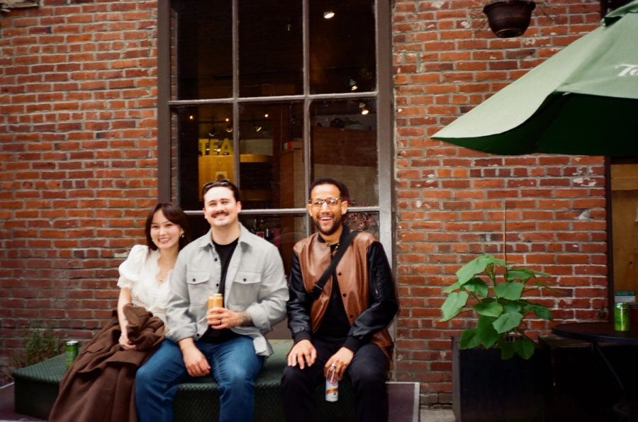 Three Sproutbox teammates sitting on a bench outside a brick building