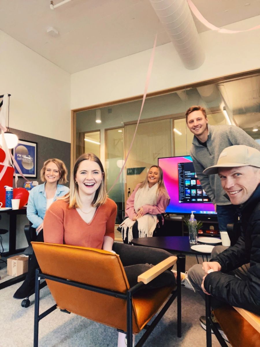 Sproutbox team smiling together in an office lounge decorated with streamers and balloons