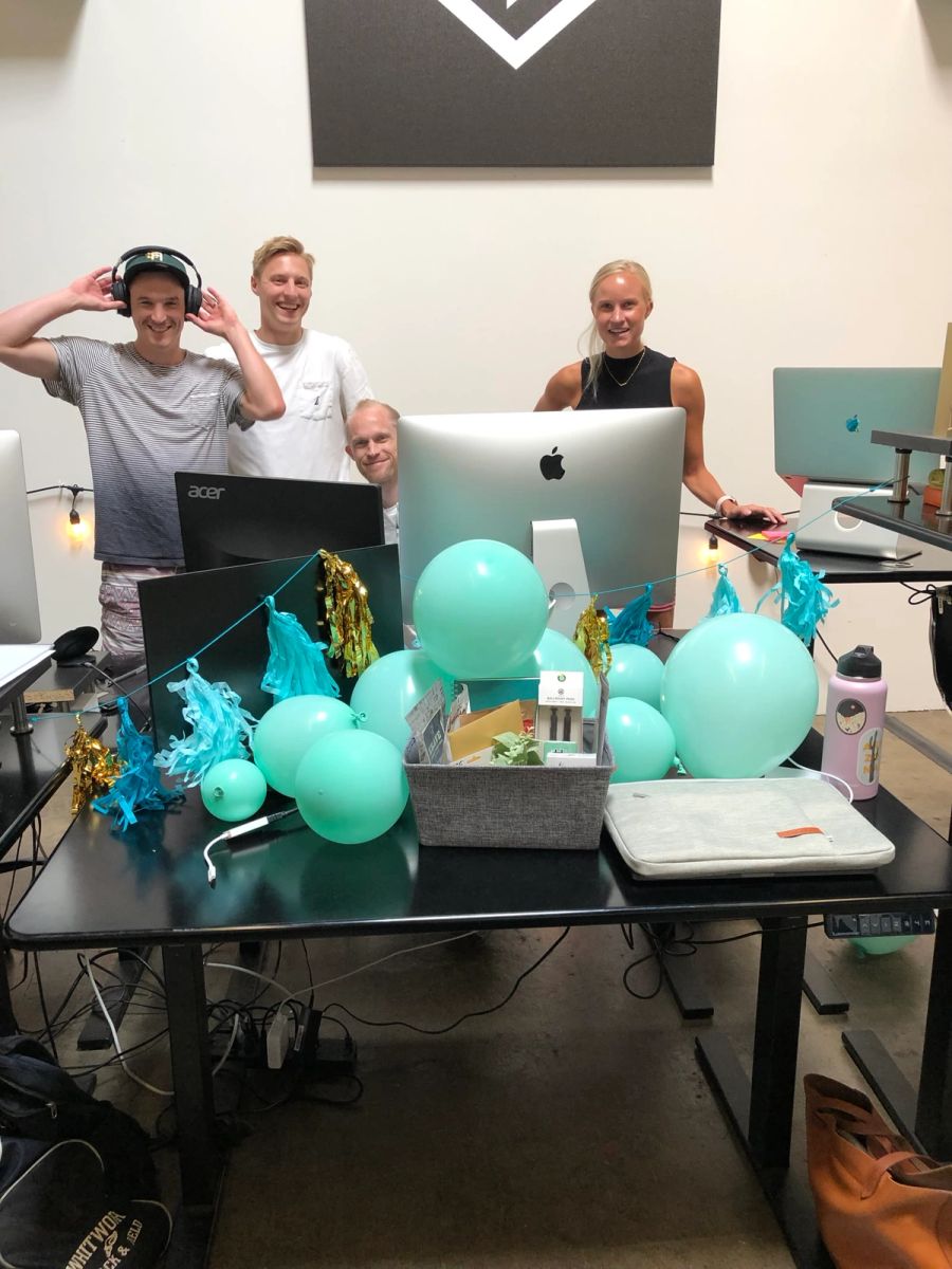 Sproutbox teammates behind a desk decorated with balloons and a welcome basket for a new hire