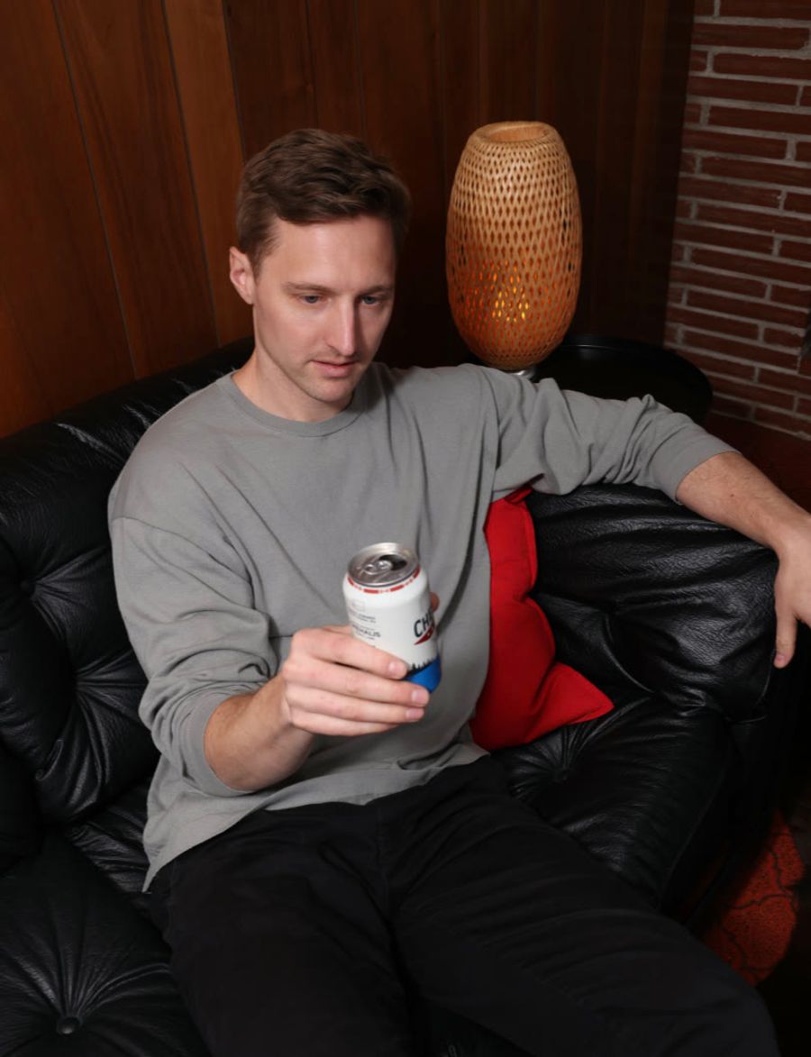 Sproutbox teammate relaxing on a leather couch with a drink