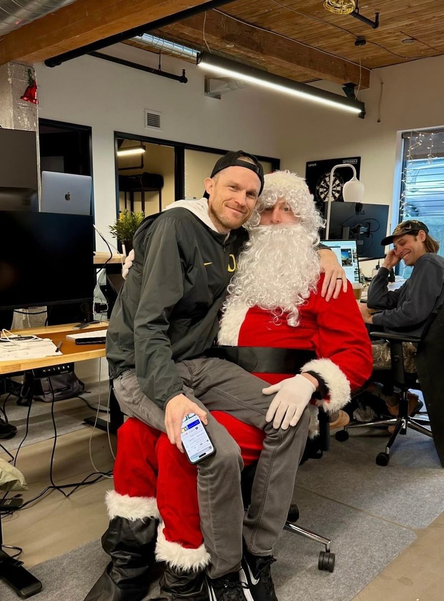 Sproutbox teammate sitting on Santa's lap in the office during the holiday party