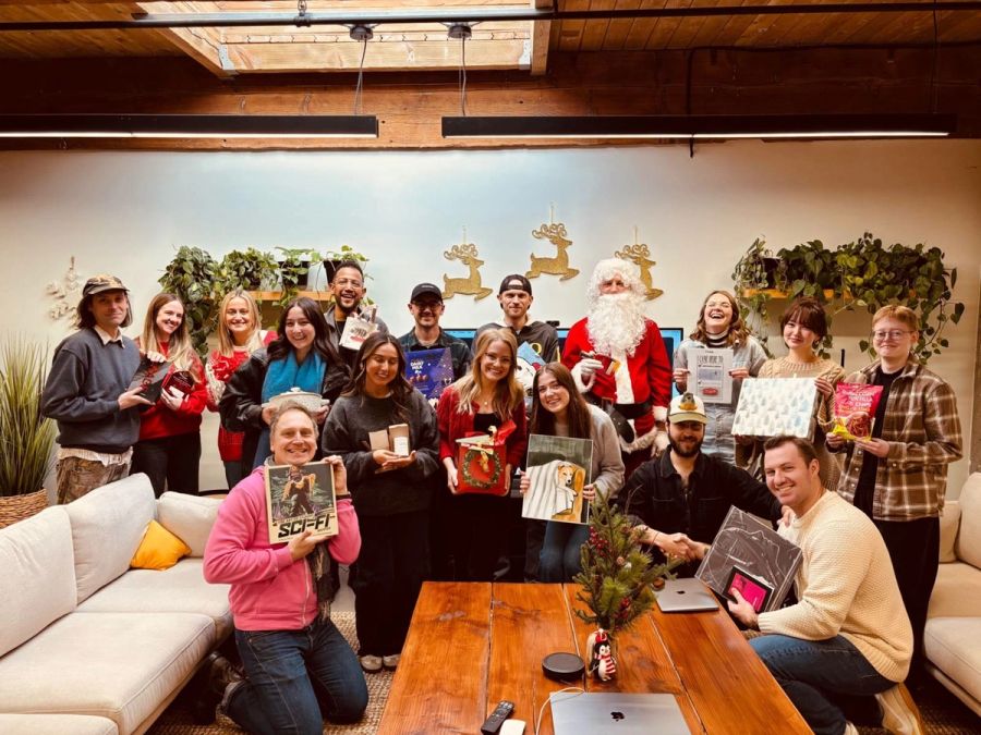 Sproutbox team and Santa holding up their gifts after the holiday gift exchange in the office lounge