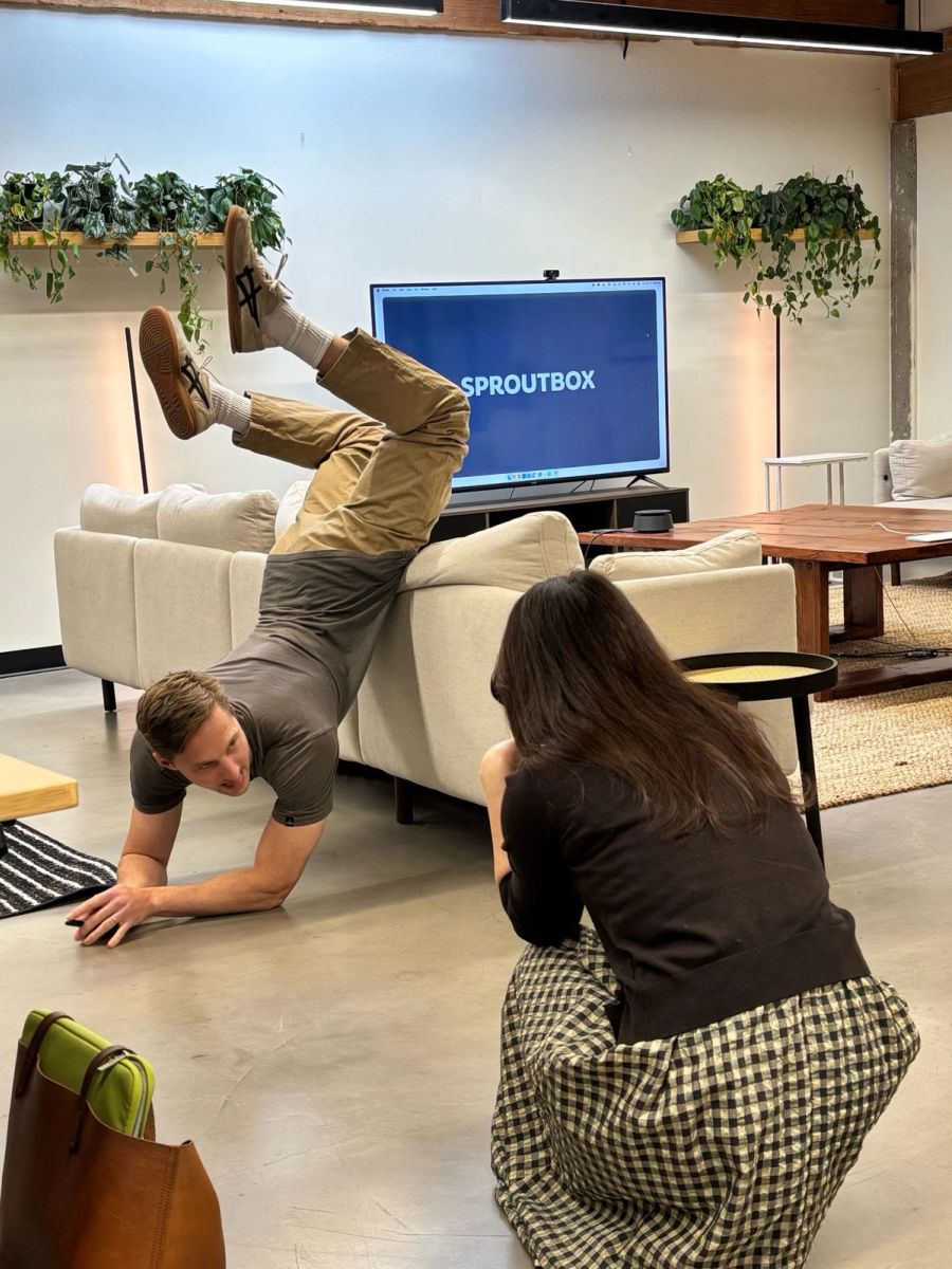 Sproutbox teammate flipping over the back of the office couch while a coworker takes the photo