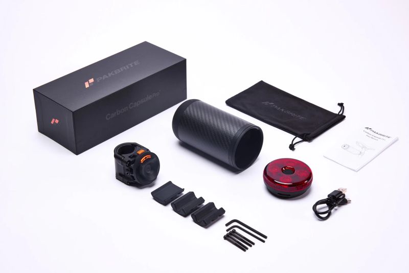 Flat lay of a carbon fiber camera accessory kit with packaging on a white background