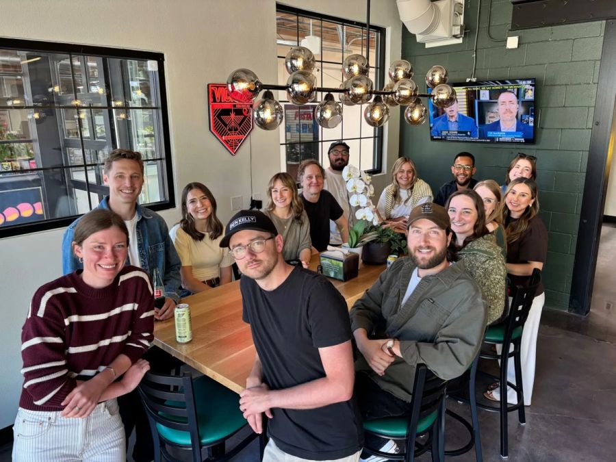 Sproutbox team gathered around a long table at a brewery with an orchid centerpiece