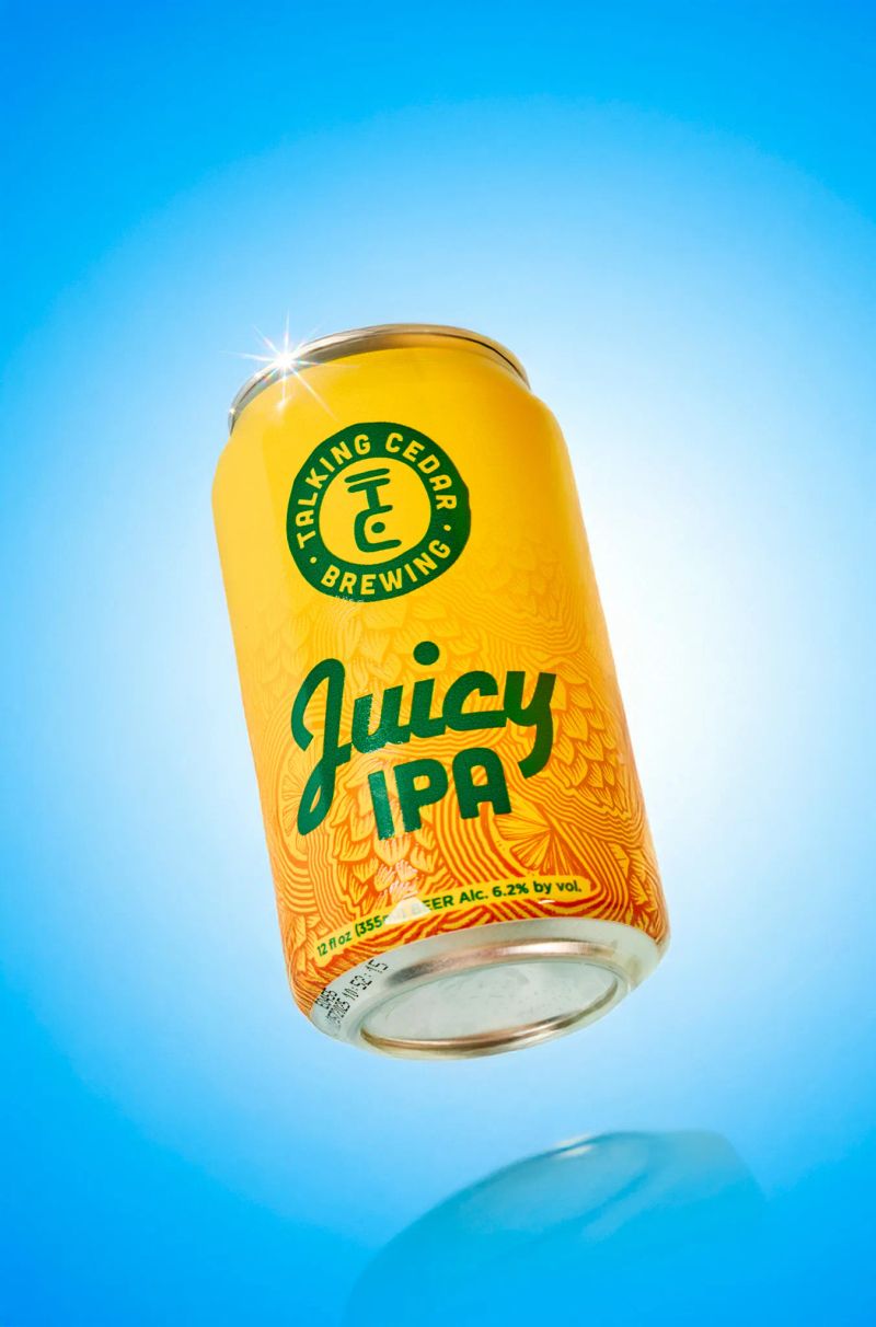 Talking Cedar Brewing Juicy IPA can floating against a bright blue background