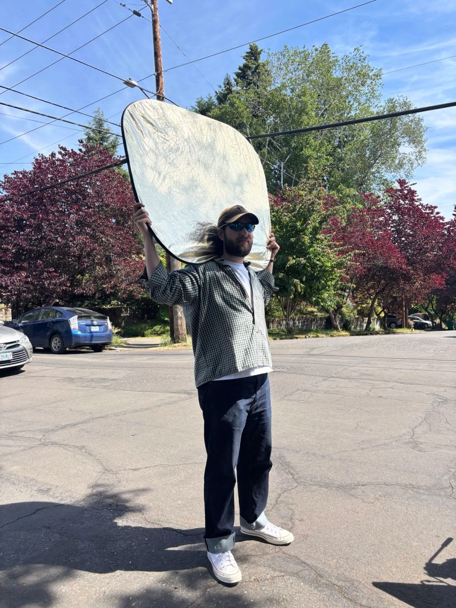 Sproutbox crew member holding up a reflector on a sunny street during a shoot