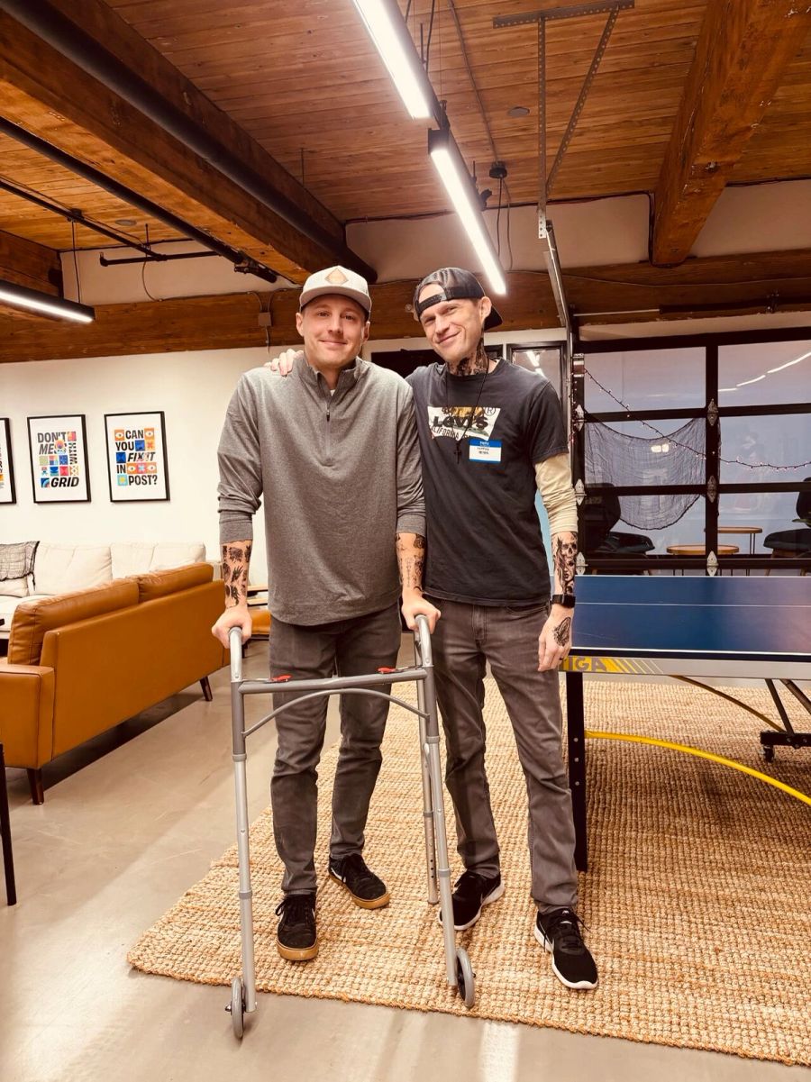 Two Sproutbox teammates in costume in the office, one leaning on a walker