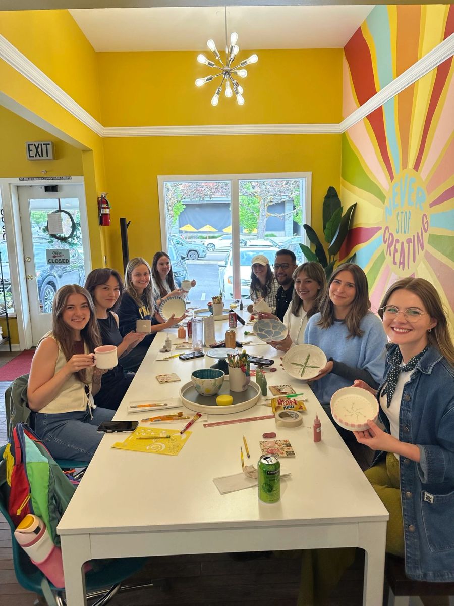 Sproutbox team painting pottery together at a long table in a bright yellow studio