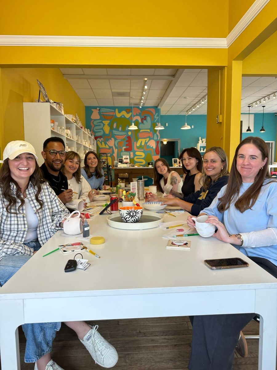 Sproutbox team gathered around a table at a pottery painting studio