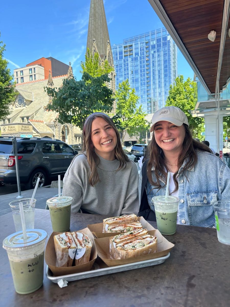 Two Sproutbox teammates having matcha lattes and sandwiches at a sidewalk cafe