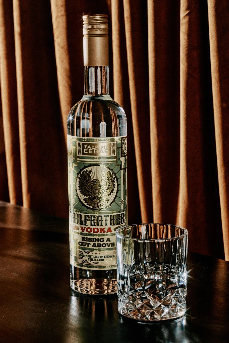 Tailfeather Vodka bottle and crystal rocks glass in front of a velvet curtain