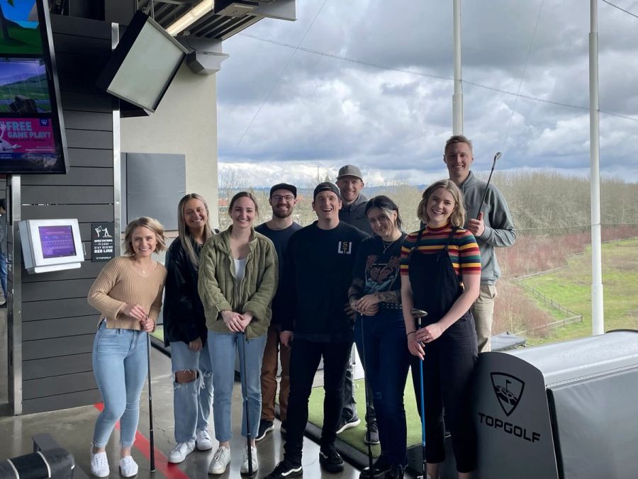 Sproutbox team holding golf clubs in their hitting bay at Topgolf