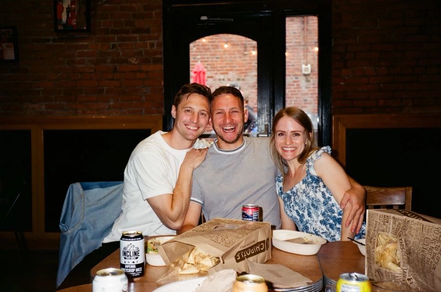 Three Sproutbox teammates smiling over takeout at a team dinner