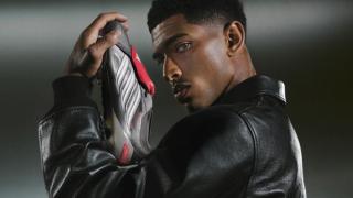 Jude Bellingham modeling the adidas Predator 26 in a "Finishers Steel" (Iron Metallic/Footwear White/Lucid Red) color scheme.