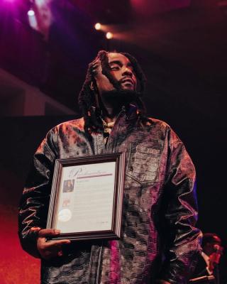 Wale holding "Wale Day" Proclamation by Washington, D.C. Mayor Muriel Bowser (2023). Photo via Wale.