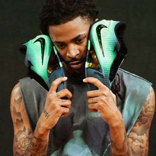 Ja Morant holding a green-and-black pair of his Nike Ja 4 basketball shoe.