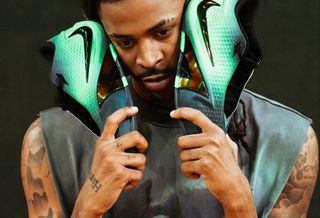 Ja Morant holding a green-and-black pair of his Nike Ja 4 basketball shoe.