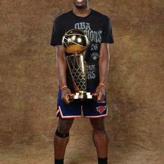 New York Knicks player OG Anunoby holding the Larry O'Brien Championship Trophy while wearing Skechers Basketball shoes.