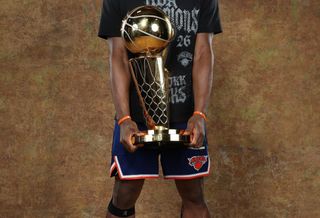 New York Knicks player OG Anunoby holding the Larry O'Brien Championship Trophy while wearing Skechers Basketball shoes.