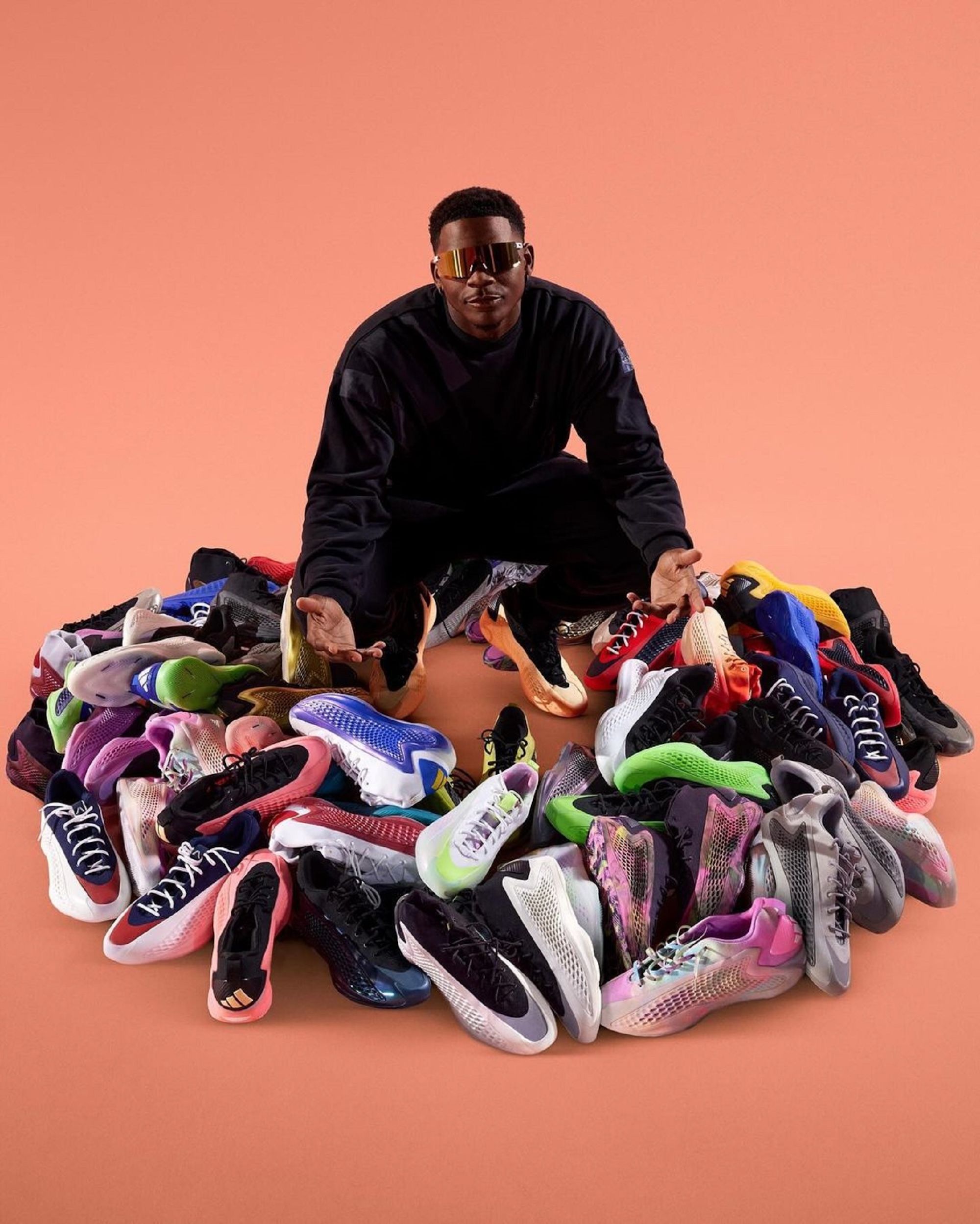 Anthony Edwards surrounded by handfuls of his Adidas Basketball Anthony Edwards 1 (AE 1) releases.