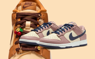 Two Nike Dunk Low sneakers showcasing "Desert Ochre" and "Particle Pink" colors, as well as cherry-shaped charms.