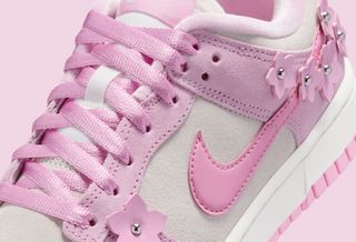 Flower-covered Nike Dunk Low in a "Pink Foam/Pink Rise/Sail/Metallic Silver" color scheme.