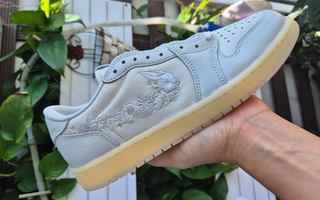 Air Jordan 1 Low OG retro in a "Sail/Off White" color scheme, complete with floral profile swooshes.