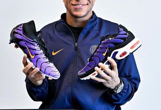 Kylian Mbappé holding two Nike footwear products.