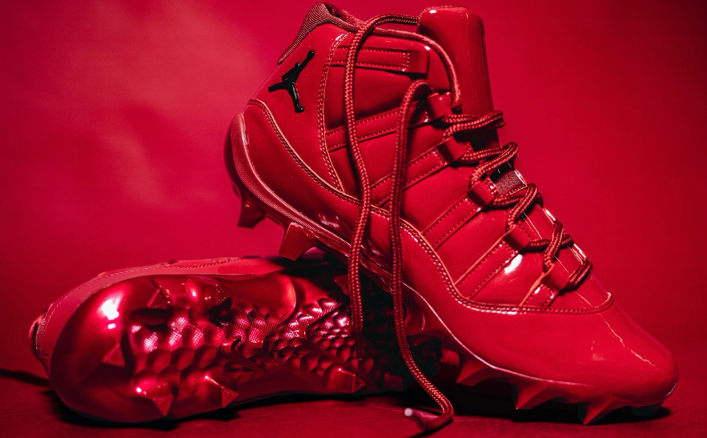 Jordan Air Jordan 11 PE cleats in Oklahoma colorway, showcasing patent leather construction and cleat configuration