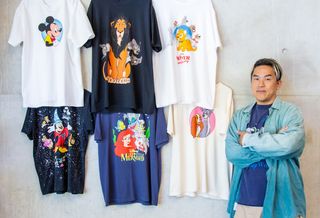 Bobby Kim, Global Creative Director, Disney Consumer Products, posing next to six graphic t-shirts from his Collection 1: Classics collaboration.