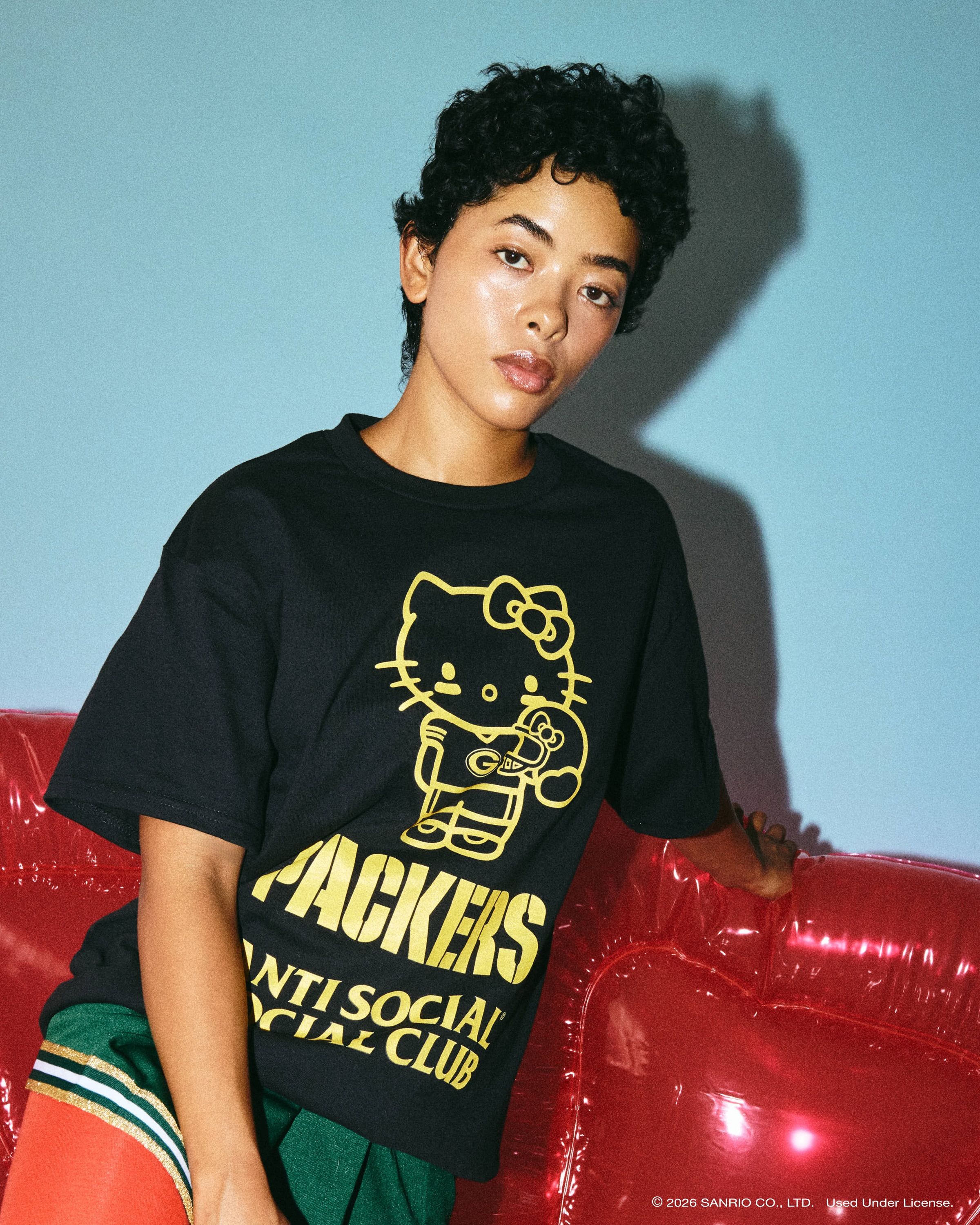 Anti Social Social Club × Hello Kitty NFL collection: black Green Bay Packers tee with yellow Hello Kitty graphic, lookbook photo via House of Heat