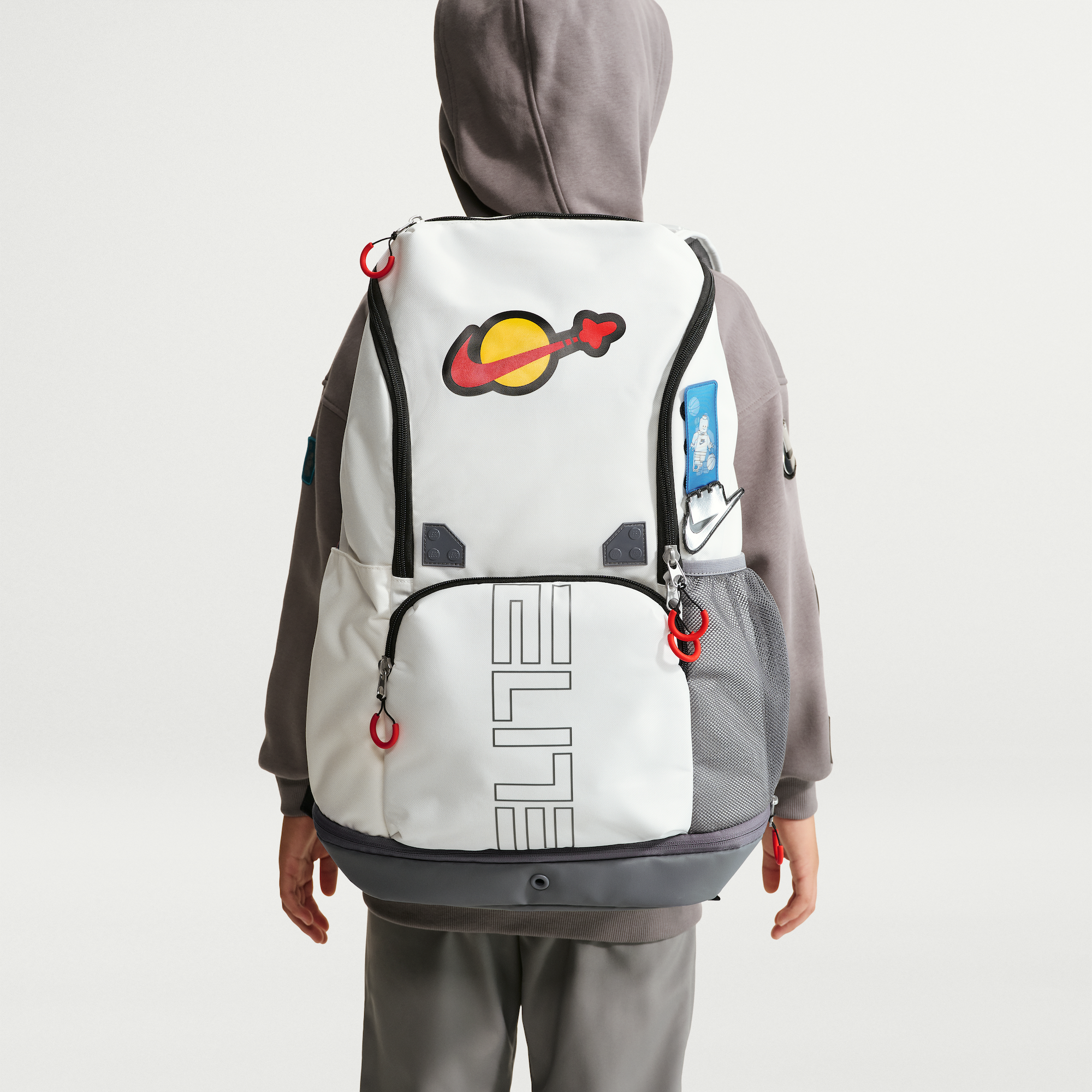 LEGO® x Nike Varsity Elite Backpack (32L) in a "Sail/Smoke Grey/Rush Red" color scheme.