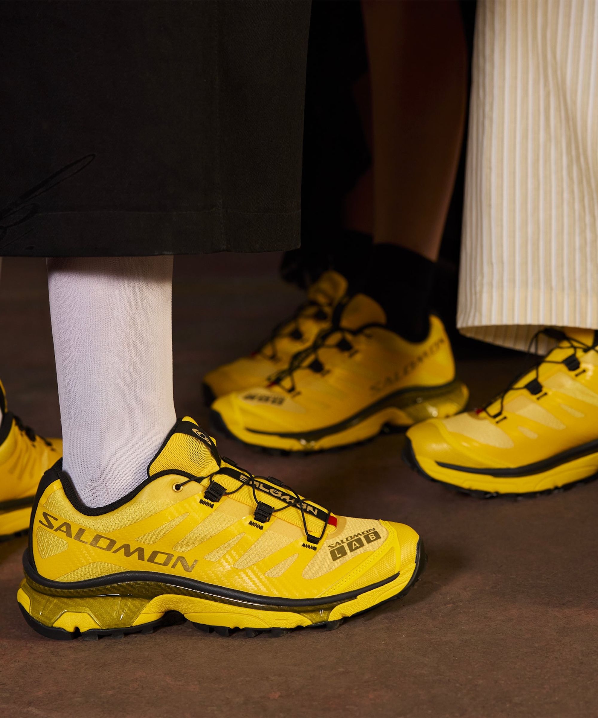 Campaign photo for Mundo Domingo x Salomon XT-4 OG sneaker collaboration in yellow-and-black.