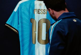 Lionel Messi standing in front of his special-edition, final Argentina Home jersey made by adidas.