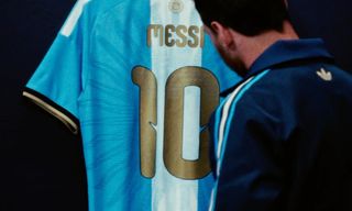 Lionel Messi standing in front of his special-edition, final Argentina Home jersey made by adidas.