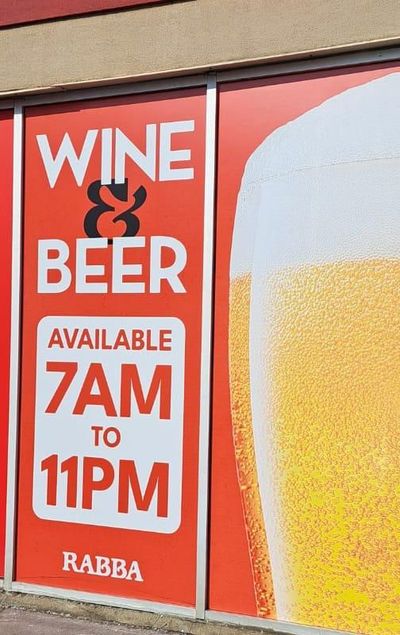 Close-up of exterior window graphics on a Rabba store: Wine and Beer lockup with legal hours 7AM to 11PM next to a large glass of beer