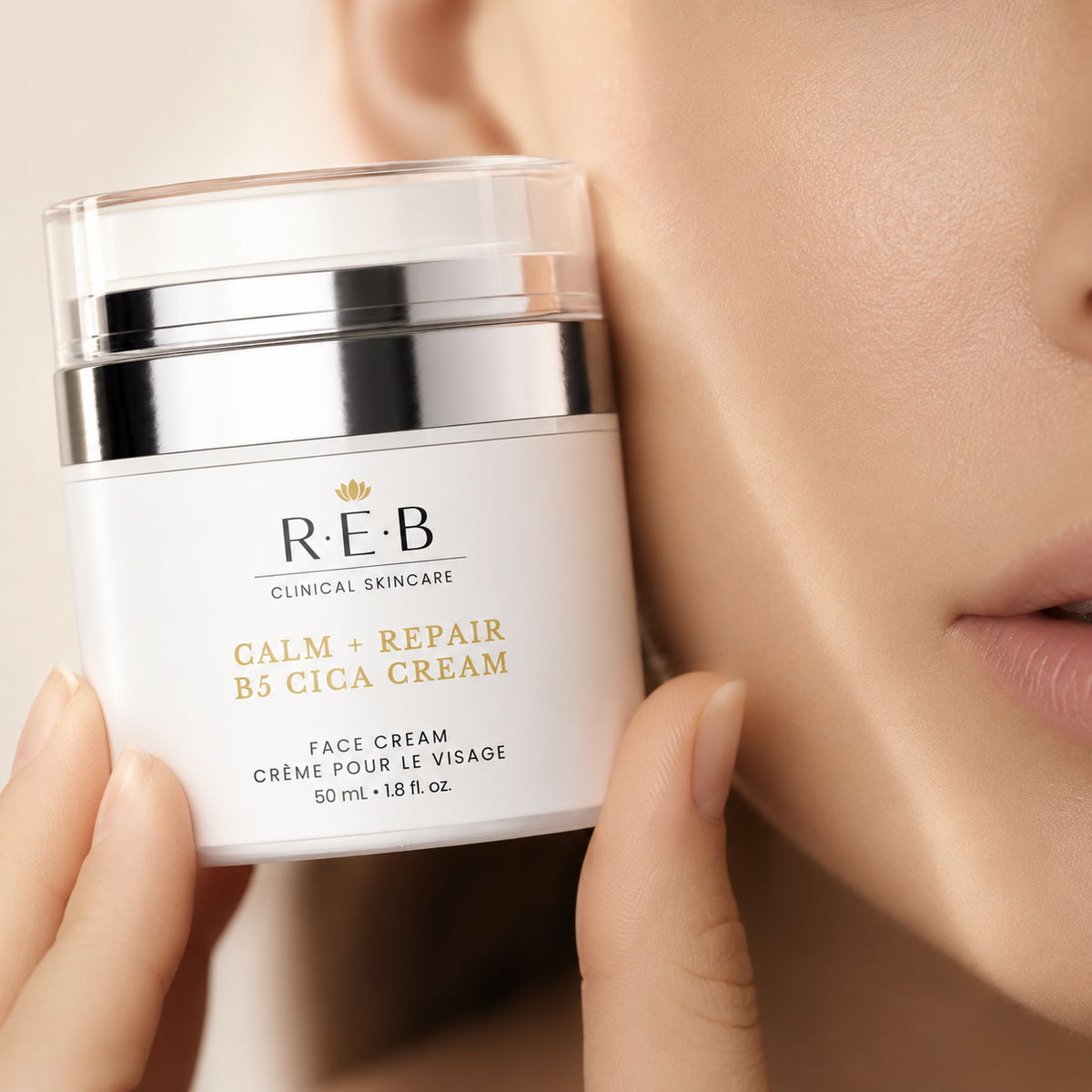 Hand holding an REB Calm + Repair B5 Cica Cream jar beside the face