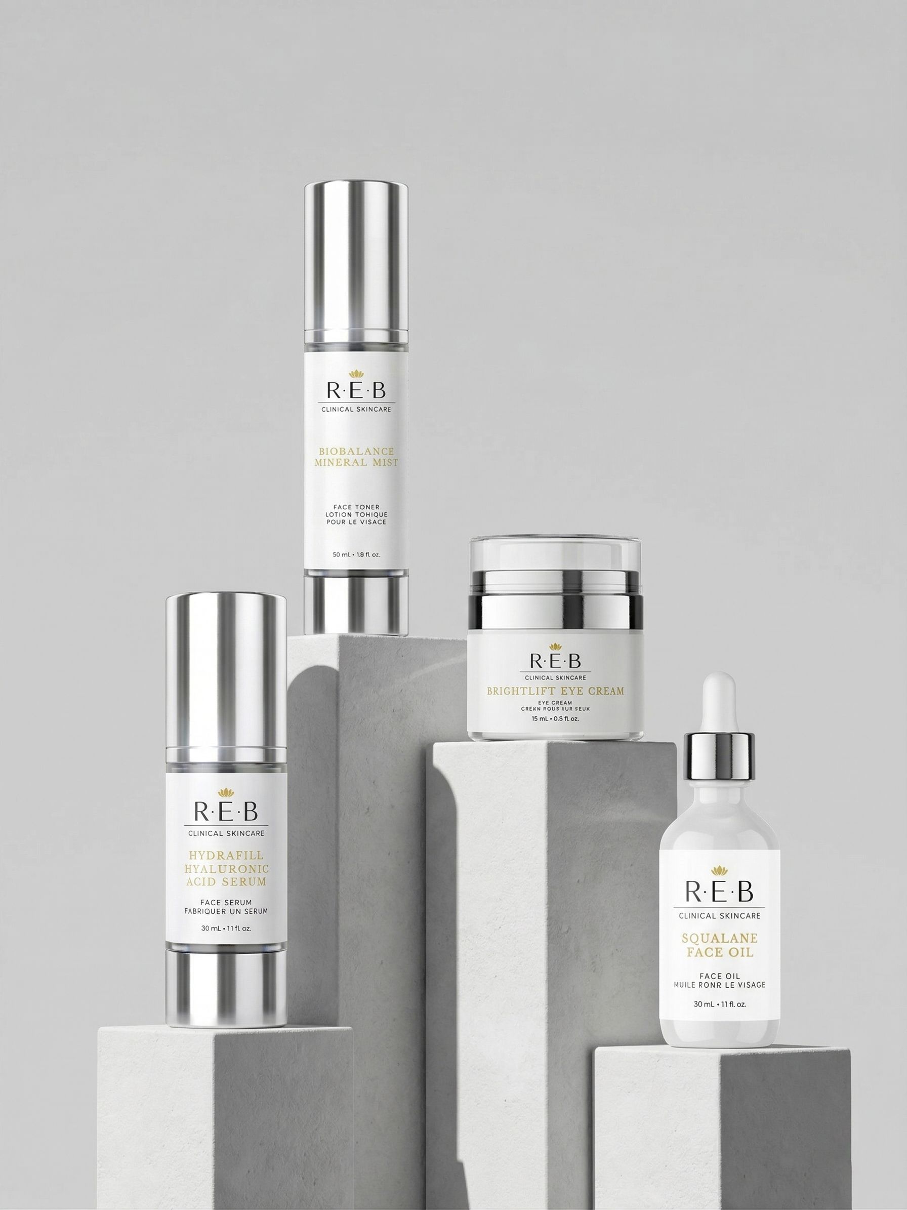 REB Clinical Skincare product line on concrete plinths: two serums, an eye cream, a face oil and a pump bottle