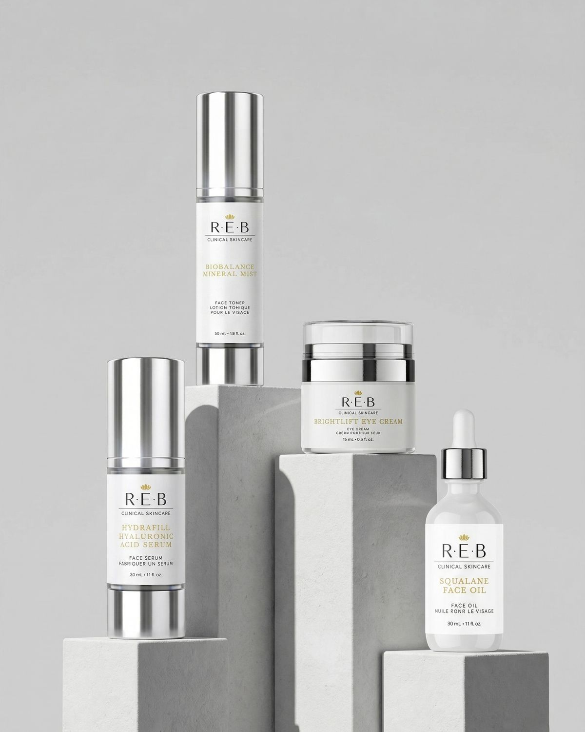 REB Clinical Skincare product line on concrete plinths: two serums, an eye cream, a face oil and a pump bottle