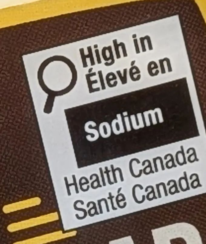 Close-up of the Health Canada front-of-pack symbol on an Ely's label: High in / Élevé en Sodium, Health Canada / Santé Canada