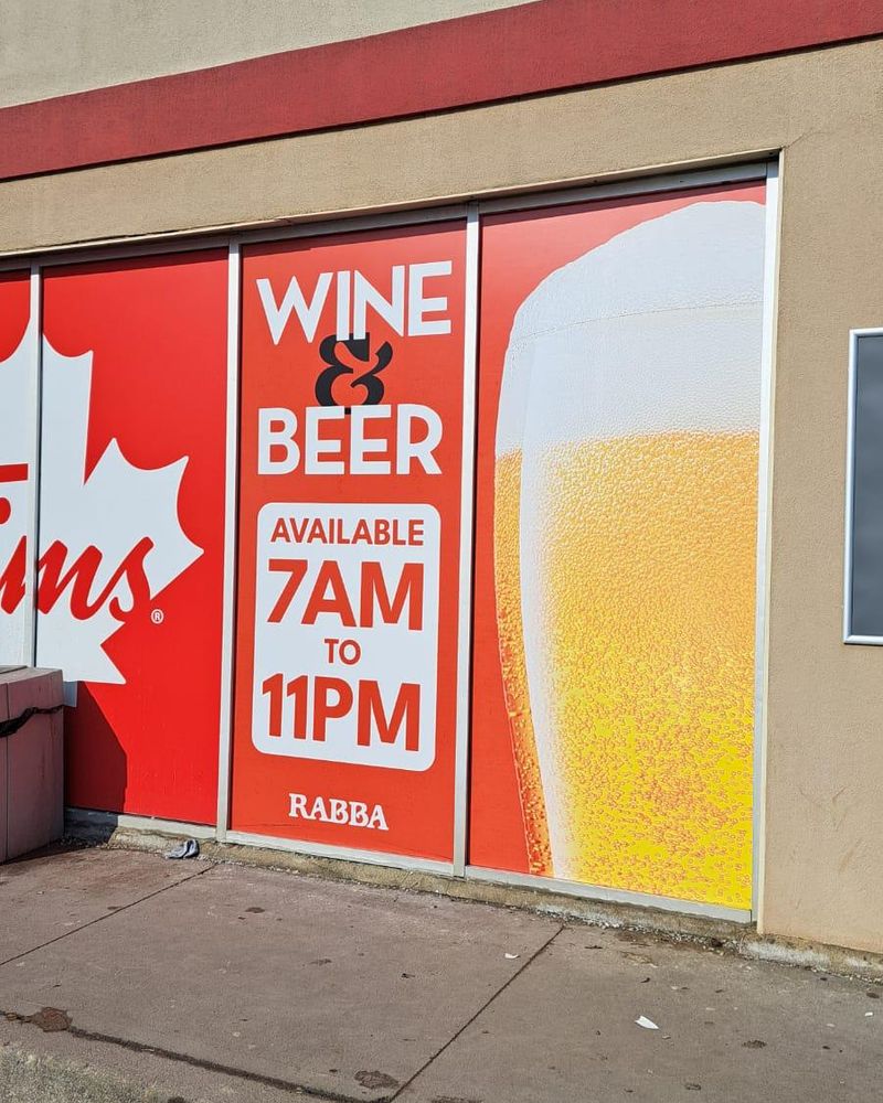 Rabba storefront window graphics reading Wine and Beer, available 7AM to 11PM, beside a full-height glass of beer