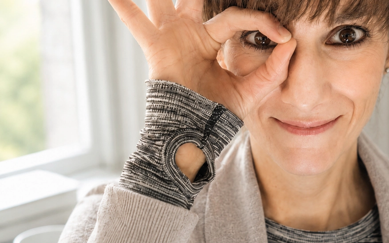 Frau schaut durch einen mit der Hand geformten Kreis