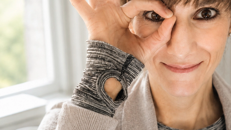 Frau schaut durch einen mit der Hand geformten Kreis