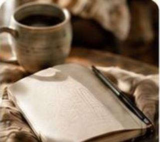 Aufgeschlagenes Notizbuch mit Stift neben einer Tasse Kaffee
