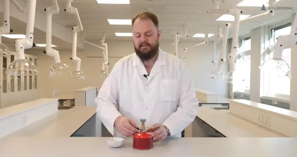 En mann i laboratoriefrakk gjør klar en gassbrenner.